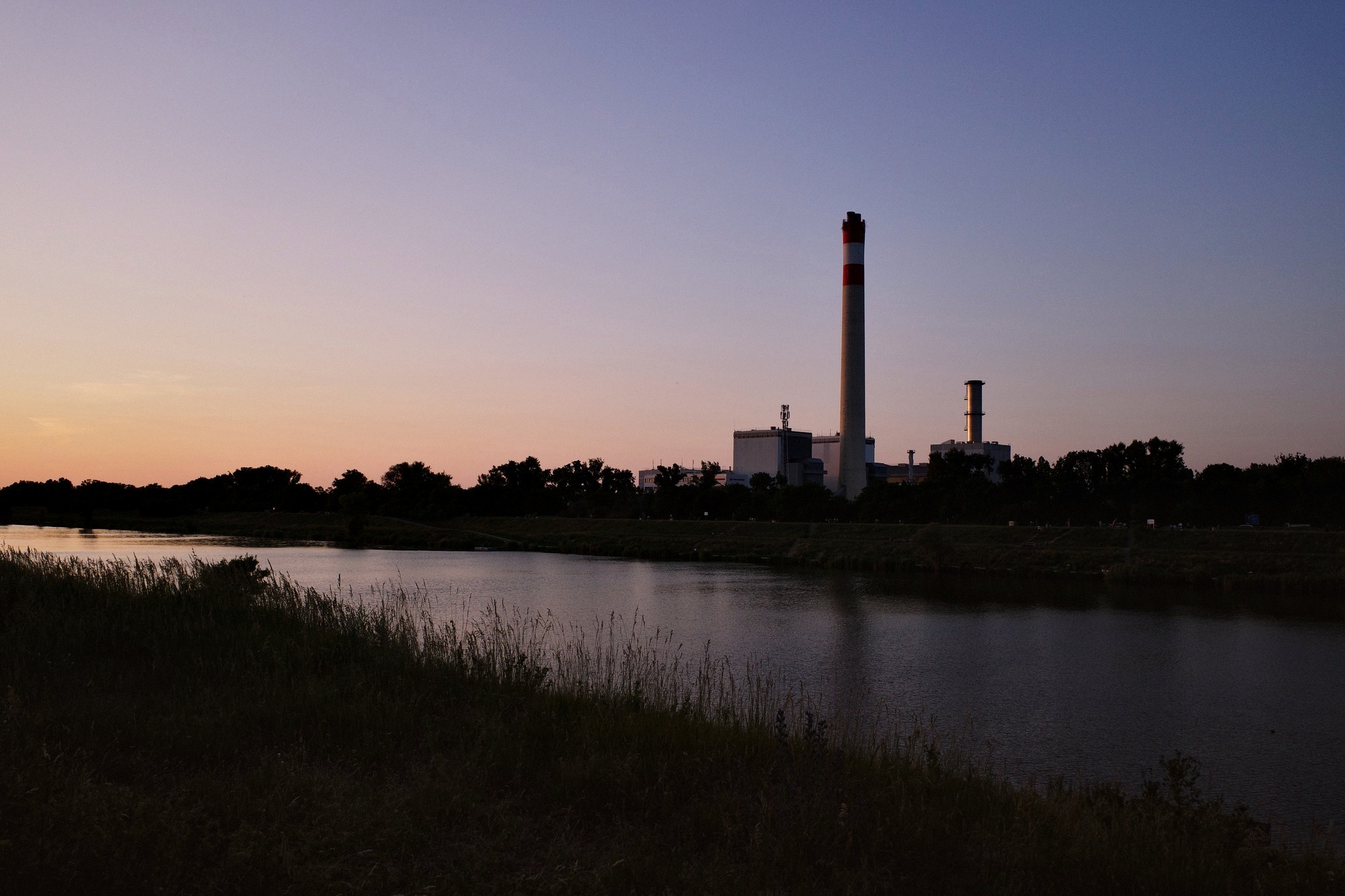 Power plant chimney at dusk beside a river